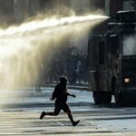 Un manifestante corre frente a un camión hidrante en Santiago, Chile, el 20 de diciembre de 2019