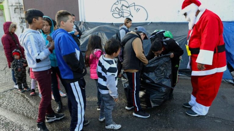 Niños migrantes reciben regalos de Navidad enviados por aficionados del equipo de fútbol FC Juárez, cerca del puente internacional Paso del Norte-Santa Fe, en Ciudad Juárez, México, el 25 de diciembre 2019