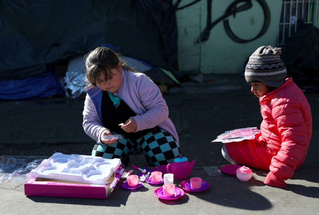 Niños migrantes con juguetes que recibieron como regalo de Navidad y que fueron enviados por aficionados del equipo de fútbol FC Juárez, cerca del puente internacional Paso del Norte-Santa Fe, en Ciudad Juárez, México, el 25 de diciembre de 2019
