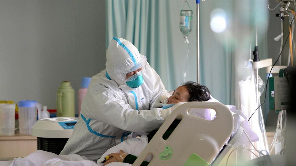 Un médico militar atiende a un paciente enfermo de coronavirus en la unidad de cuidados intensivos, en China