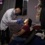 Un profesional de la salud examina a una mujer en su casa de Sao Paulo para averiguar si es un caso más de coronavirus en Brasil