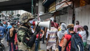 Un agente de la Fuerza Boliviariana de Venezuela explica a la población que debe regresar a sus hogares a causa de la cuarentena decetada por el Gobierno