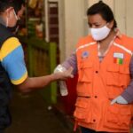 Una mujer aplica desinfectante de manos a un cliente a la entrada de un mercado municipal en la ciudad guatemalteca de San Marcos