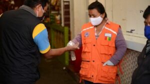 Una mujer aplica desinfectante de manos a un cliente a la entrada de un mercado municipal en la ciudad guatemalteca de San Marcos