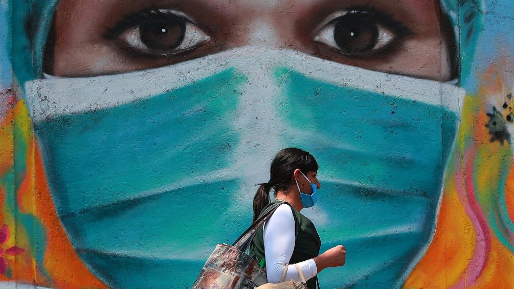 Una mujer camina por las calles de Ciudad de México frente a un mural pintado en homenaje a los trabajadores de la salud durante la pandemia de la COVID-19