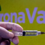 Jeringuilla frente al logotipo de CoronaVac, vacuna china contra el coronavirus