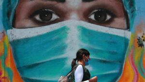 Una mujer camina por las calles de Ciudad de México frente a un mural pintado en homenaje a los trabajadores de la salud durante la pandemia de la COVID-19