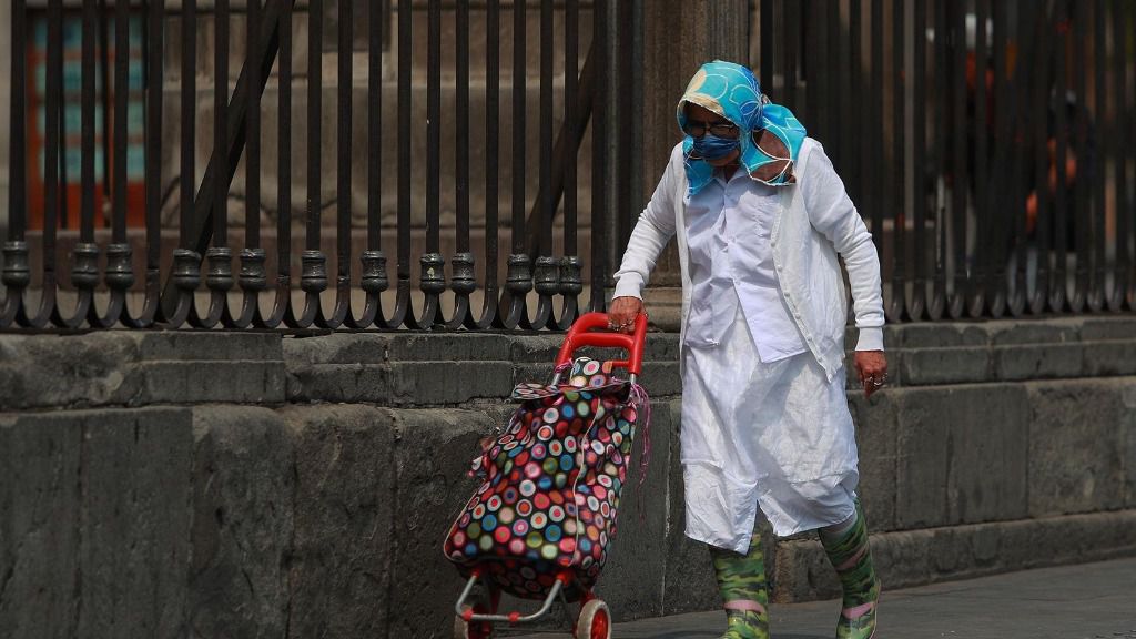 Una mujer con mascarilla y bata en una calle de México