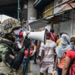 Un agente de la Fuerza Boliviariana de Venezuela explica a la población que debe regresar a sus hogares a causa de la cuarentena decetada por el Gobierno