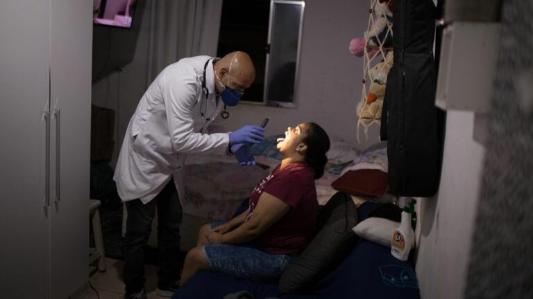 Un profesional de la salud examina a una mujer en su casa de Sao Paulo para averiguar si es un caso más de coronavirus en Brasil