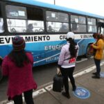 Un grupo de personas mantienen las distancias sociales mientras esperan en una parada de autobús de Lima, Perú