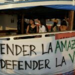 Indígenas descansan en la flotilla Yaku Mama Amazon, proveniente de Ecuador, que llegó el 9 de noviembre a Belém (Brasil) después de navegar 3 000 km por el río Amazonas. / EFE | Antonio Lacerda