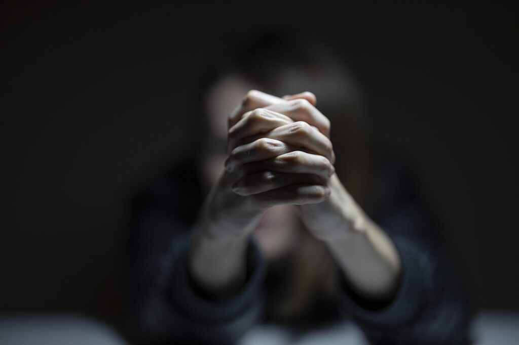 Mujer con las manos entrelazadas en un fondo oscuro