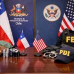 Mesa con banderas de Chile y EEUU, equipo policial y minerales